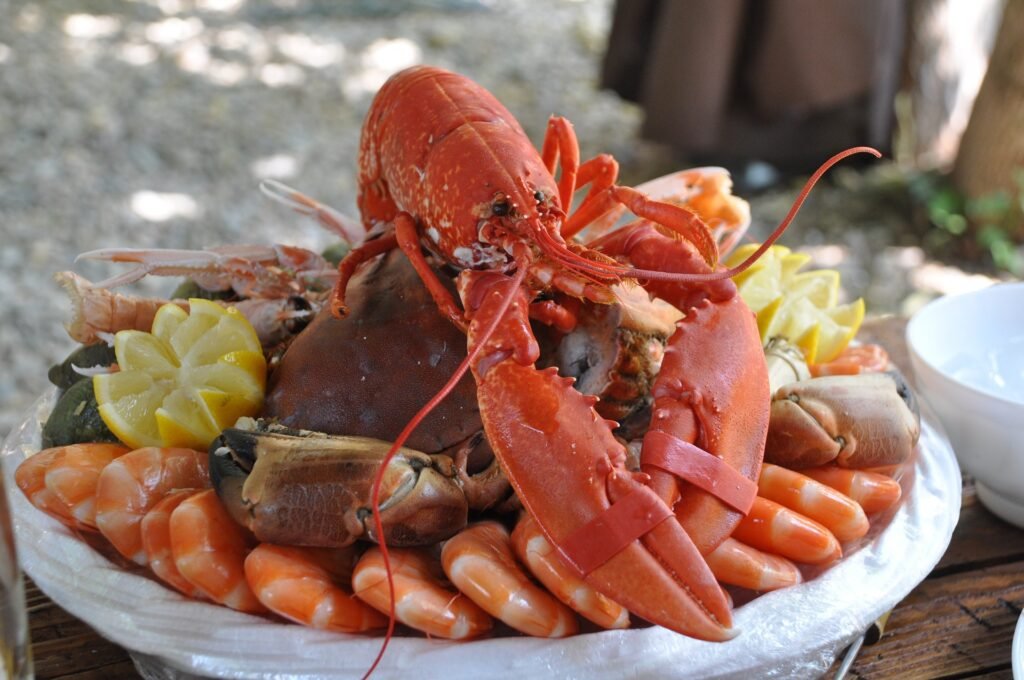 Plato de mariscada con una langosta, limones cortados, un cangrejo, gambas...